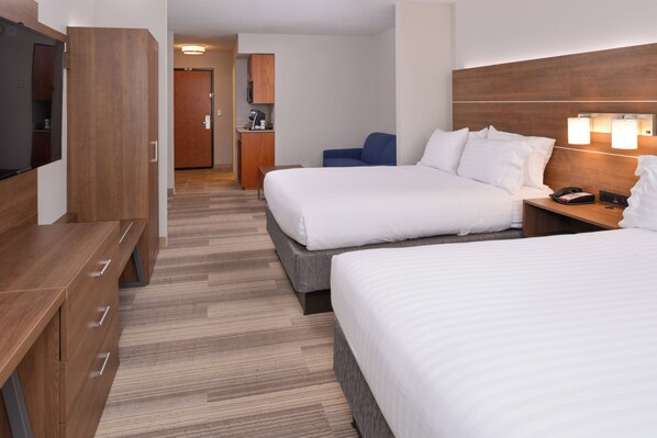 Habitación de hotel con dos camas, un escritorio, un televisor y una kitchenette.