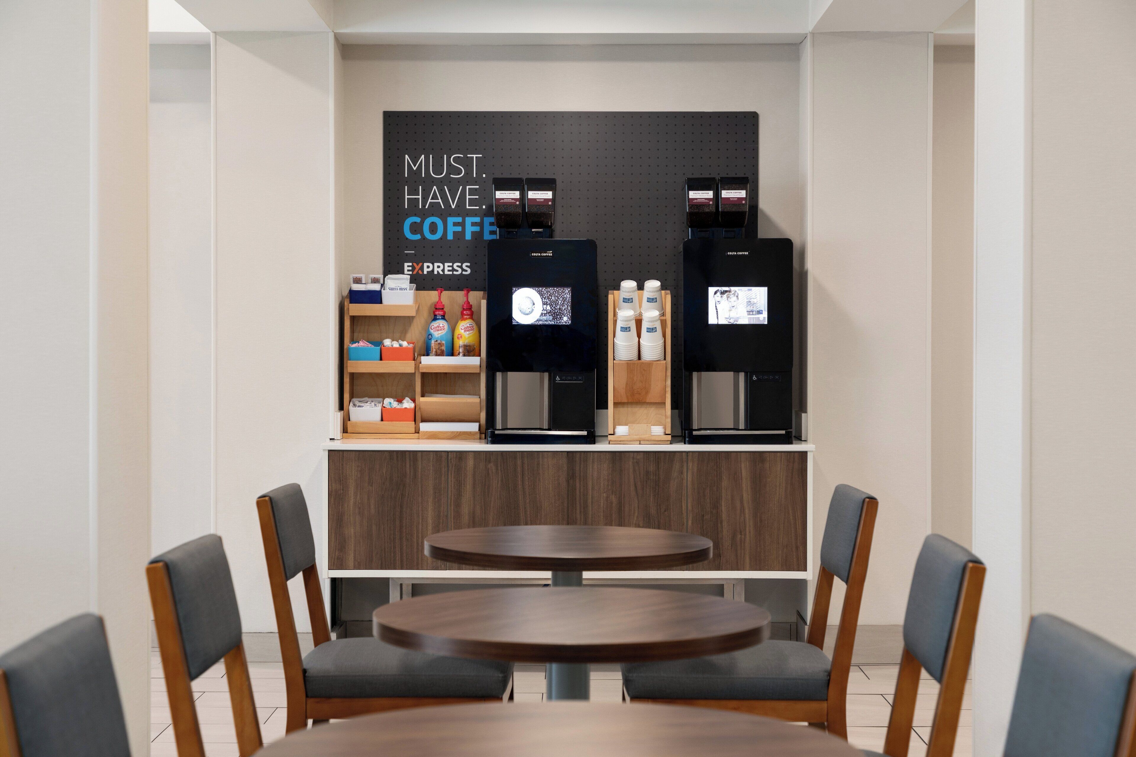 Un café doté de deux machines à expresso et d’une étagère où sont présentés divers produits à base de café.