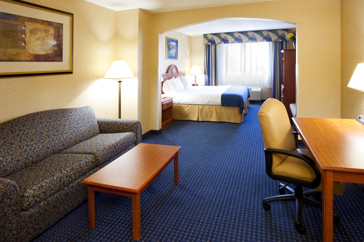 A hotel room with a sofa, a bed, a desk, and a chair.