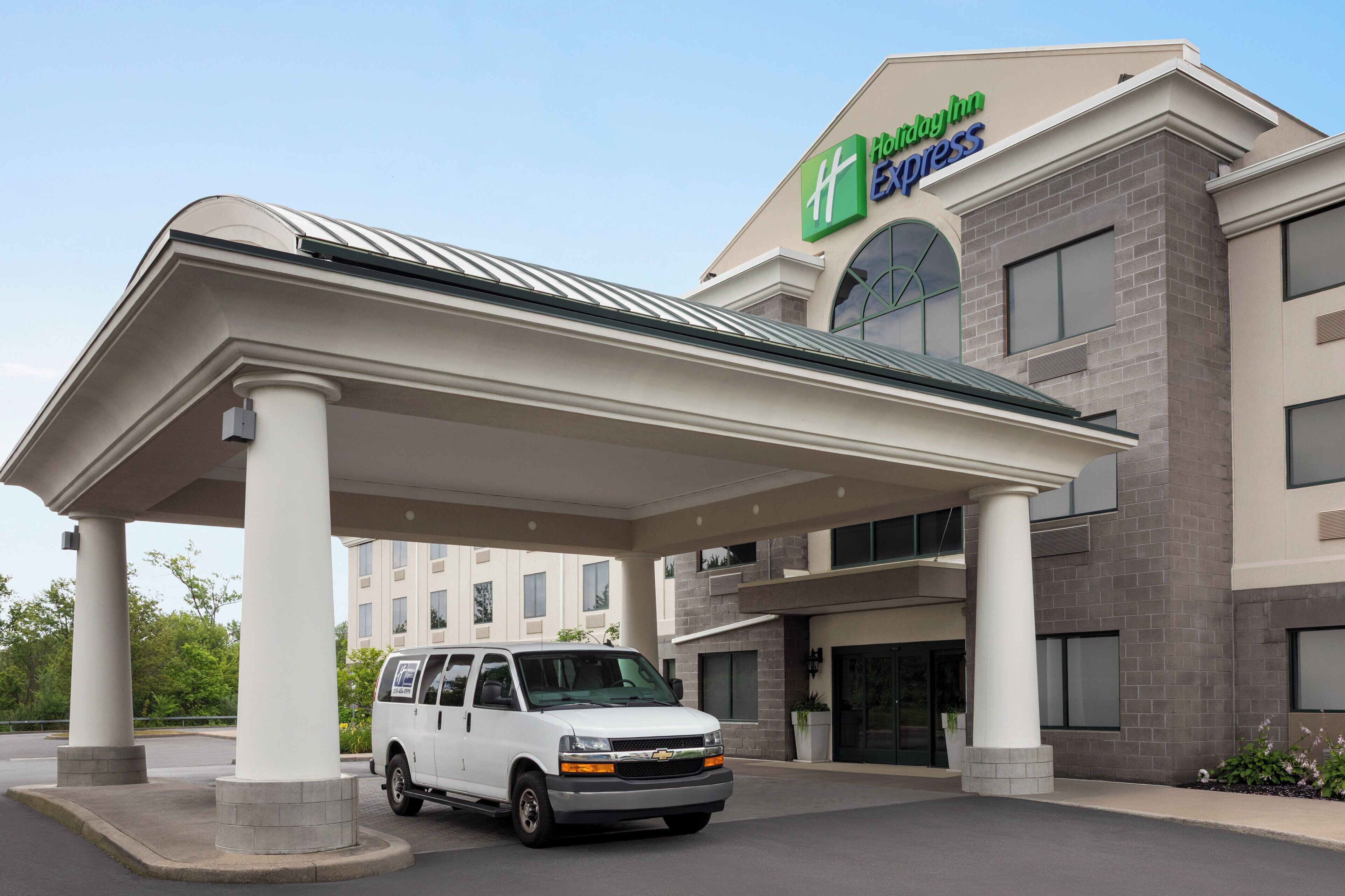 A Holiday Inn Express building with a covered parking area and a white van parked in front.