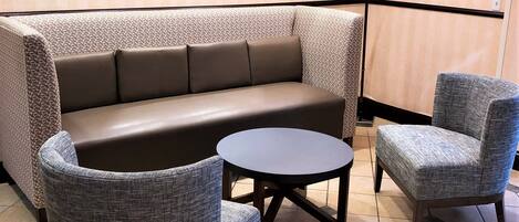 A seating area with a sofa and two armchairs, a small round table, and a mirror on the wall.