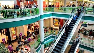 Un centre commercial à plusieurs niveaux, doté d’escalators reliant les différents étages, de nombreux magasins et d’un atrium central avec des espaces de repos.