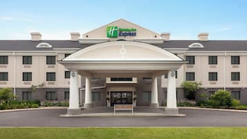 Der Eingang eines Holiday Inn Express Hotels mit überdachter Auffahrt und einer Sitzbank in der Mitte.