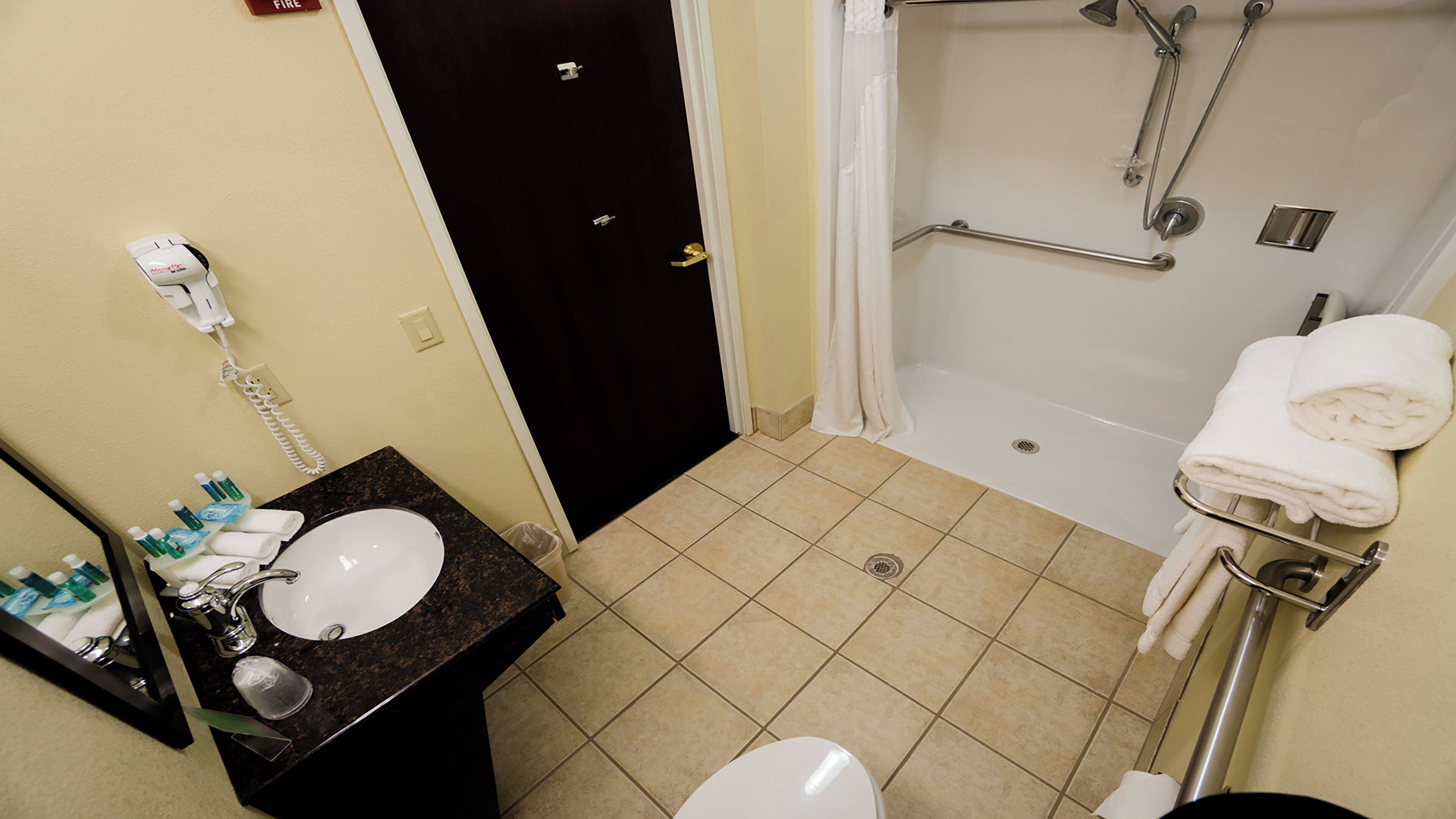 A bathroom with a sink, toilet, shower, and towel rack.