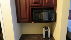 A kitchen with a microwave oven mounted above a countertop, a coffee maker on the counter, and wooden cabinets. - Holiday Inn Express & Suites Pampa by IHG (Pampa)