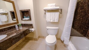 Une salle de bain avec des toilettes, un lavabo et un miroir. On y trouve des serviettes et des articles de toilette sur le comptoir.