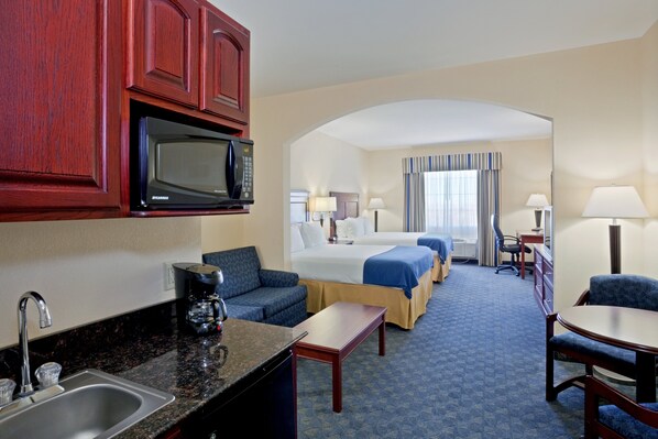 Une chambre d’hôtel équipée d’une kitchenette, d’un lit, d’un bureau et d’un coin salon.