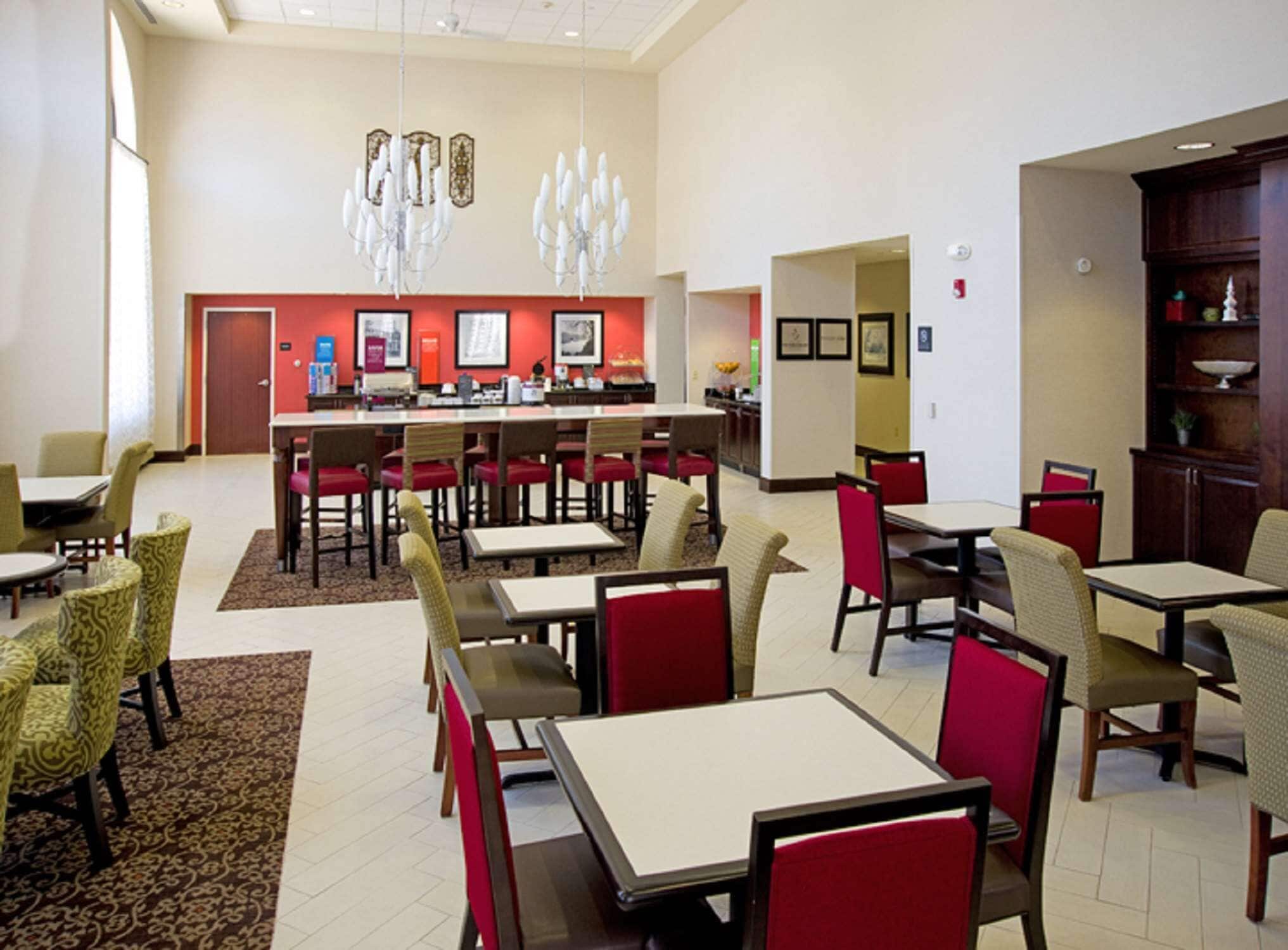 Un comedor espacioso con varias mesas y sillas, una barra central y decoración en las paredes.