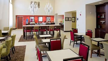 Un comedor espacioso con varias mesas y sillas, una barra central y decoración en las paredes.
