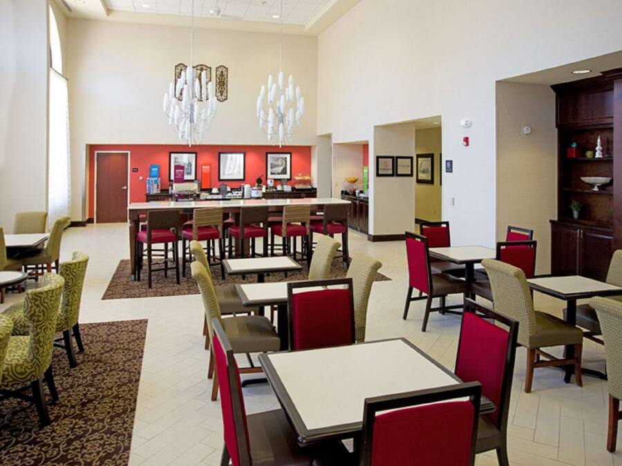 Un comedor espacioso con varias mesas y sillas, una barra central y decoración en las paredes.