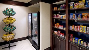 A snack bar with a refrigerator and shelves stocked with various snacks and beverages.