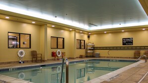 An indoor swimming pool with safety railings, lifebuoys, and a no diving sign.