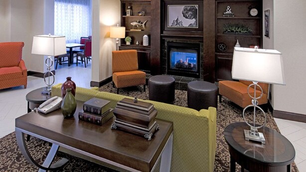A hotel lobby with a fireplace, seating area, and a television.