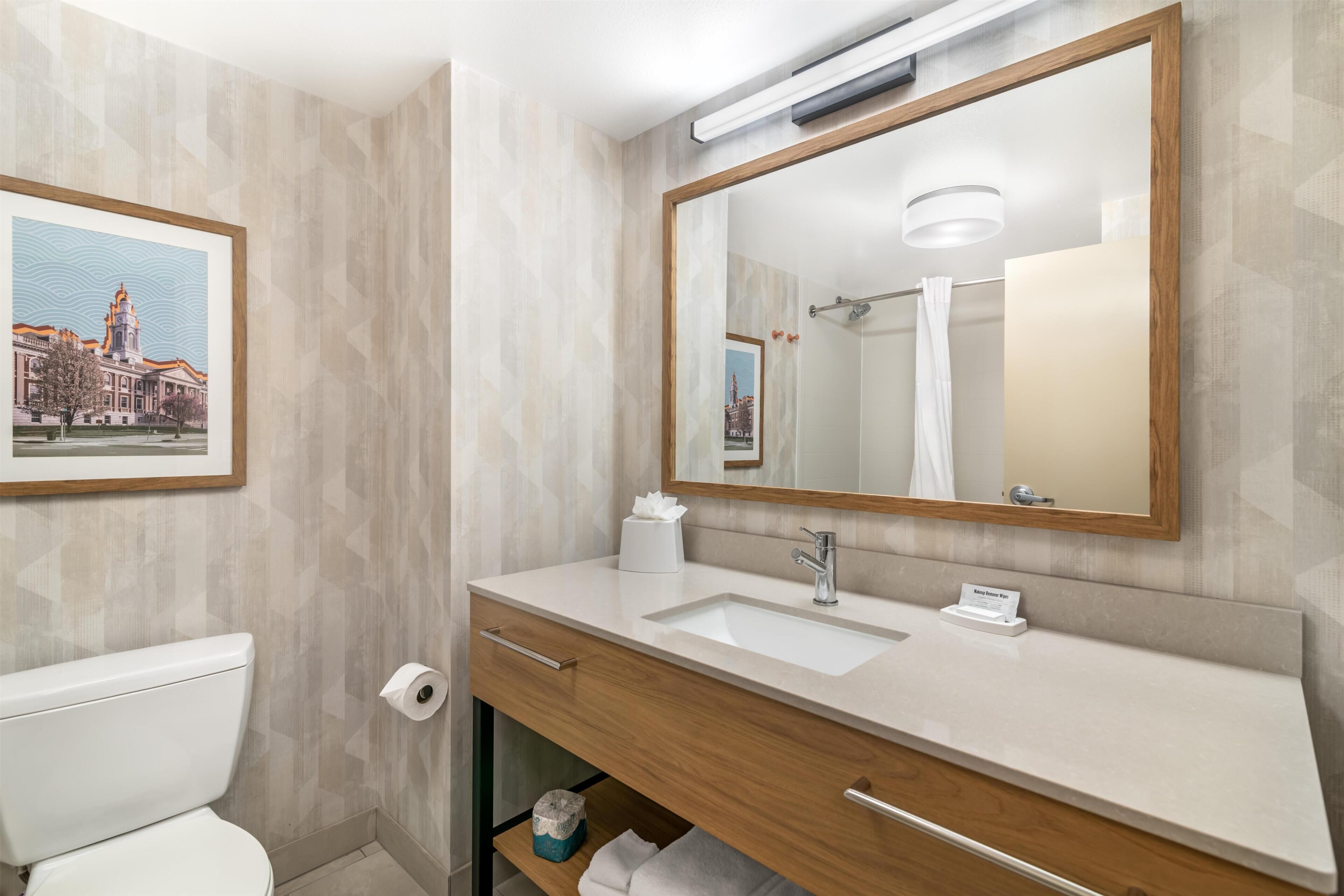 Une salle de bain équipée de toilettes, d’un lavabo, d’un miroir et d’un porte-serviettes.