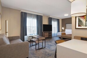 Une chambre d’hôtel équipée d’un canapé, d’un bureau, d’une télévision, d’un lit et d’une table à manger.