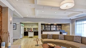 A modern living room with a sofa, coffee table, and a dining area with a kitchen in the background.