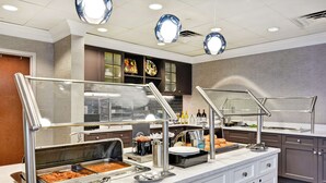 A buffet setup with various food items and a self-service station.