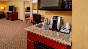 A hotel kitchenette with a microwave, coffee maker, and sink.