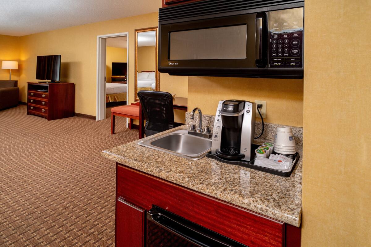 A hotel kitchenette with a microwave, coffee maker, and sink.