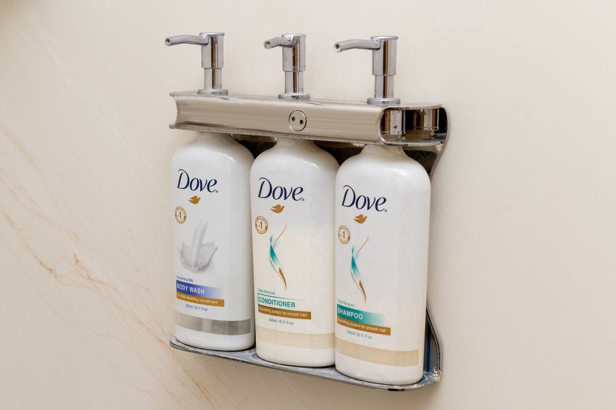 Three Dove body wash bottles on a wall-mounted shelf.