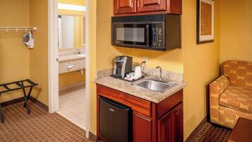A compact kitchenette with a microwave, coffee maker, and sink.