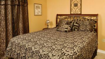 A bedroom with a large bed, a nightstand, a lamp, and a framed picture on the wall.