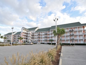 A multi-story hotel with balconies, a parking lot, and a clear sky.