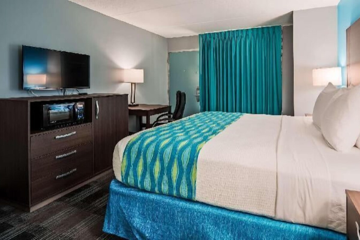 Une chambre d’hôtel avec un lit, une télévision, un bureau et une chaise.