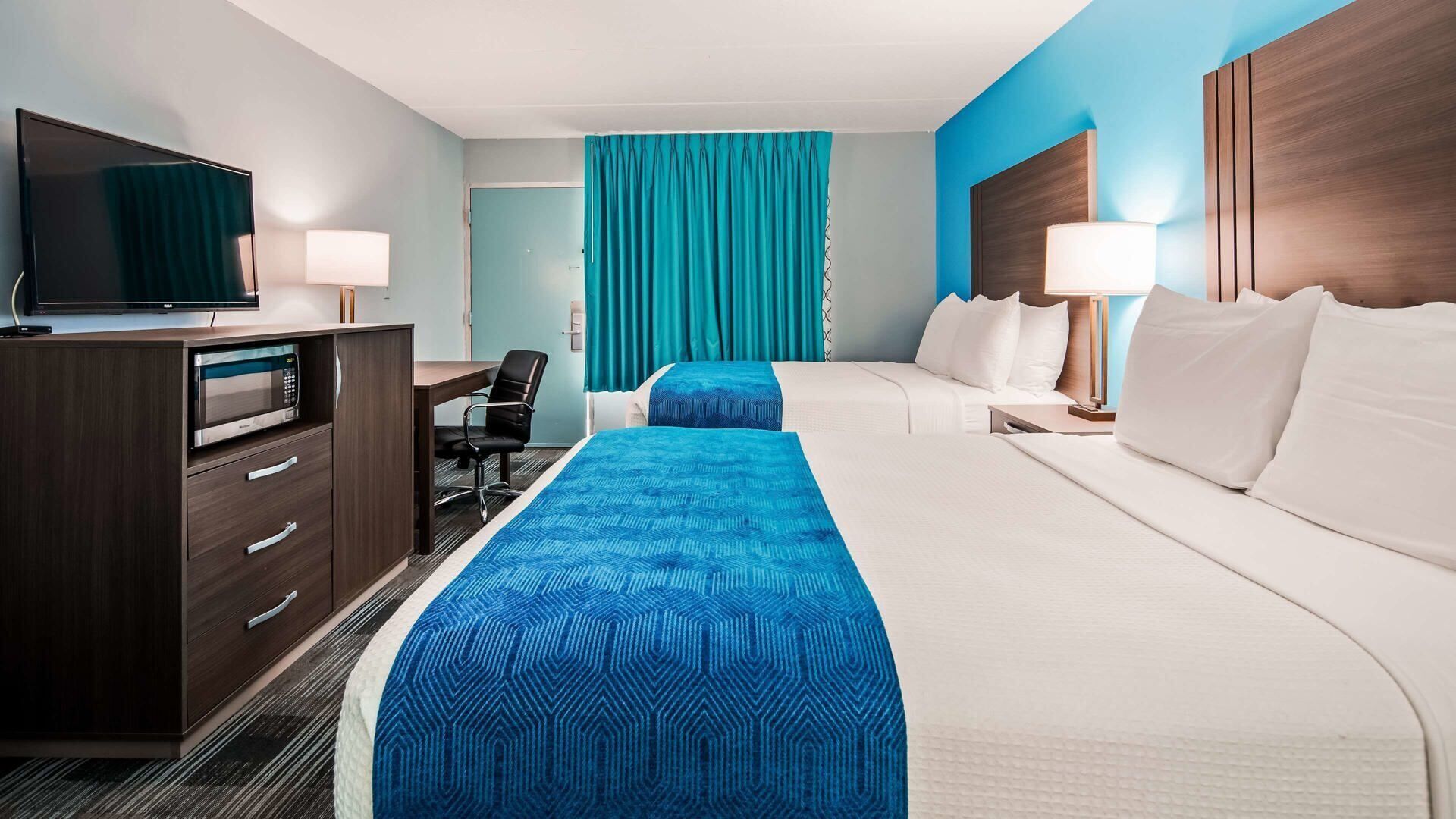 Una habitación de hotel con una cama, un escritorio, un televisor y un microondas.