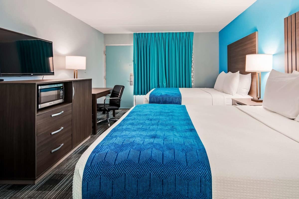 A hotel room with a bed, a desk, a television, and a microwave.