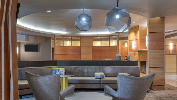 Un espace de détente moderne avec un aménagement circulaire des sièges, une table centrale et des luminaires suspendus aux formes géométriques.
