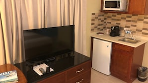 Cocina compacta con microondas, lavamanos y refrigerador.