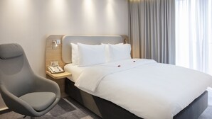 A hotel room with a bed, a chair, a nightstand with a phone, and a window with curtains. - Holiday Inn Express Baden-Baden by IHG (Baden-Baden)