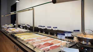 A buffet with various food options and utensils.