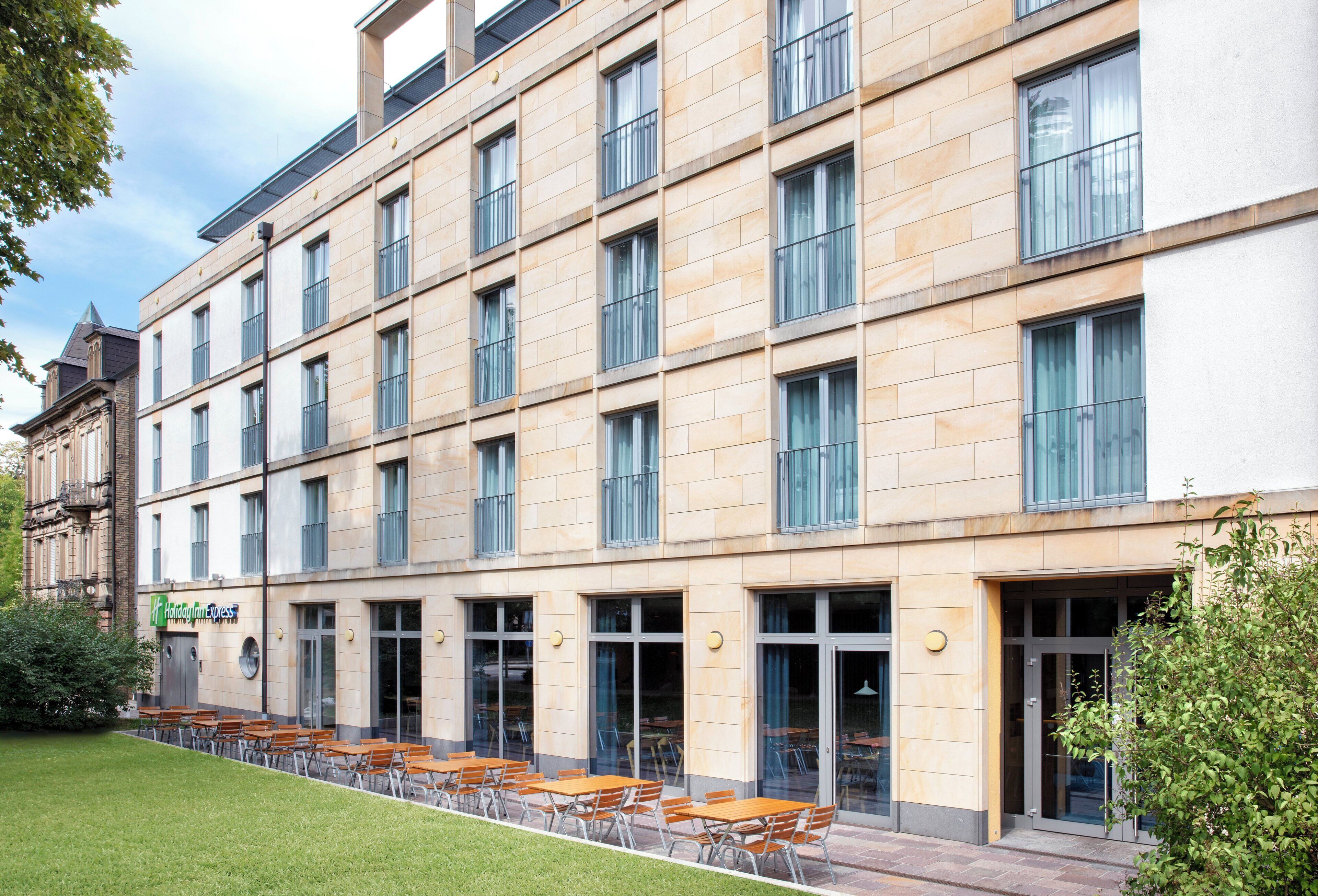Ein mehrgeschossiges Hotel mit schlichter Fassade, großen Fenstern und einer Außenbereichs-Sitzgelegenheit.