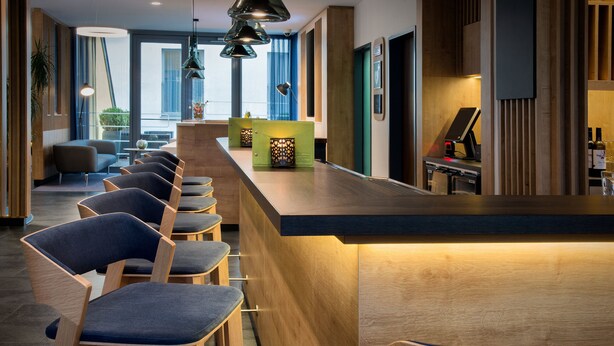 A modern bar area with wooden bar stools and pendant lighting. - Holiday Inn Express Baden-Baden by IHG (Baden-Baden)