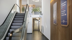 An indoor staircase leading to a second-floor area with a wooden panel wall and a sign indicating WLAN connectivity.