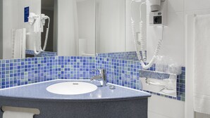 A bathroom with a sink, mirror, and hair dryer mounted on the wall. - Holiday Inn Express Baden-Baden by IHG (Baden-Baden)