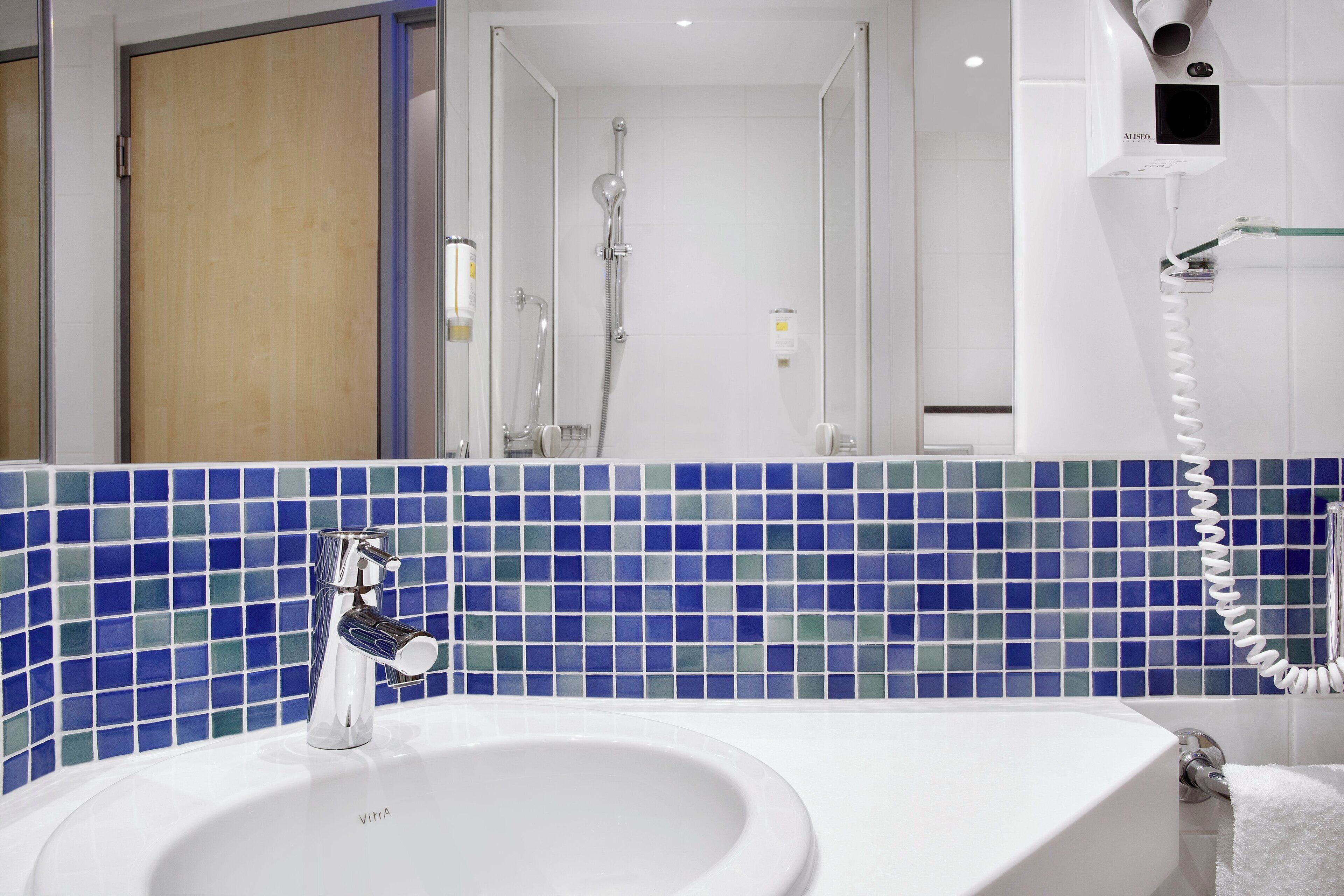 A bathroom with a white sink, a mirror, and a shower.