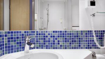 A bathroom with a white sink, a mirror, and a shower.