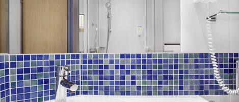 A bathroom with a white sink, a mirror, and a shower.