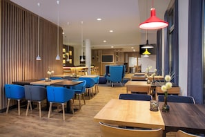 A modern restaurant interior with wooden panel walls, blue upholstered chairs, and a variety of pendant lights. - Holiday Inn Express Baden-Baden by IHG (Baden-Baden)