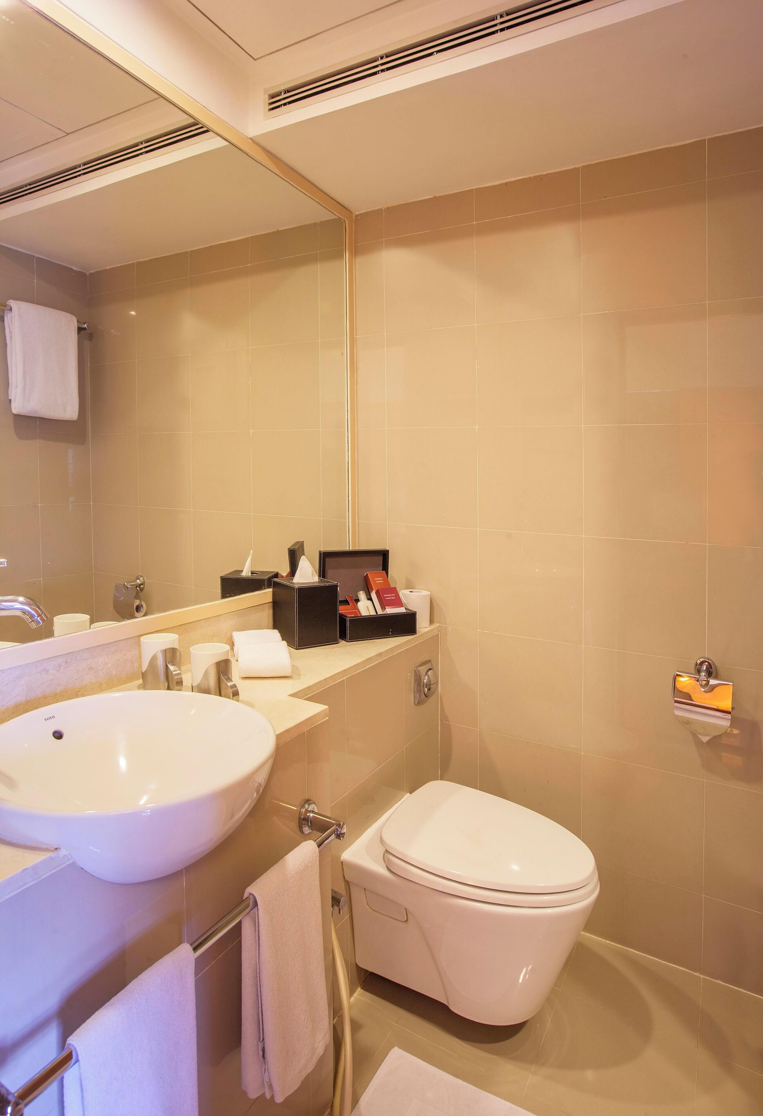 Un baño con lavamanos, inodoro y espejo.