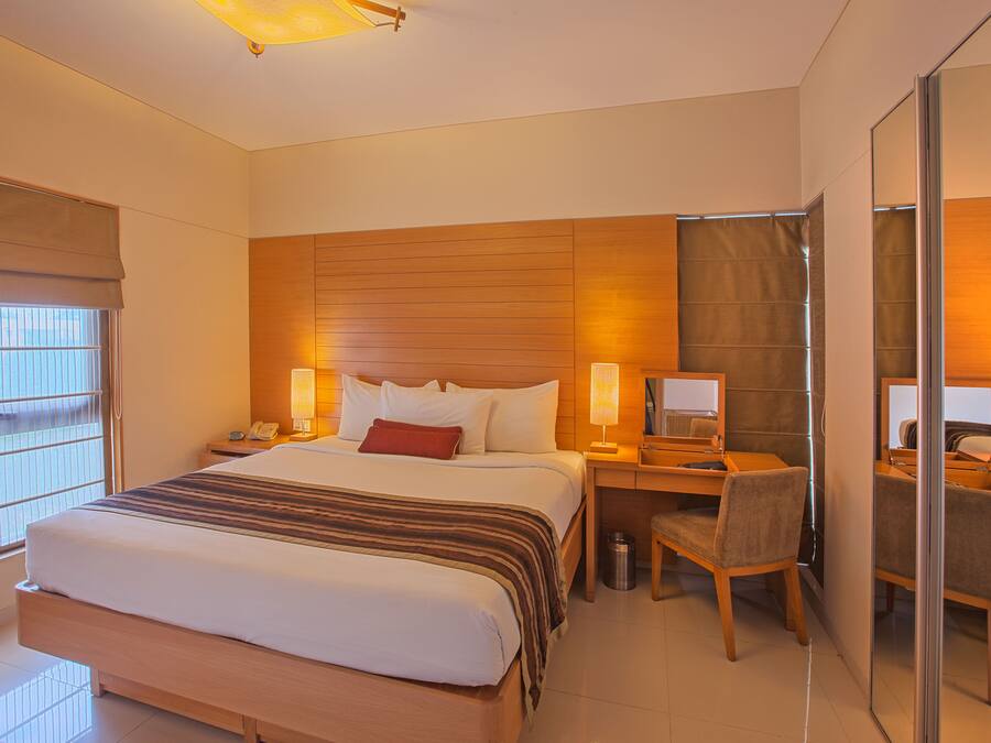 Una habitación de hotel con una cama grande, un escritorio con una silla, una computadora y un espejo.