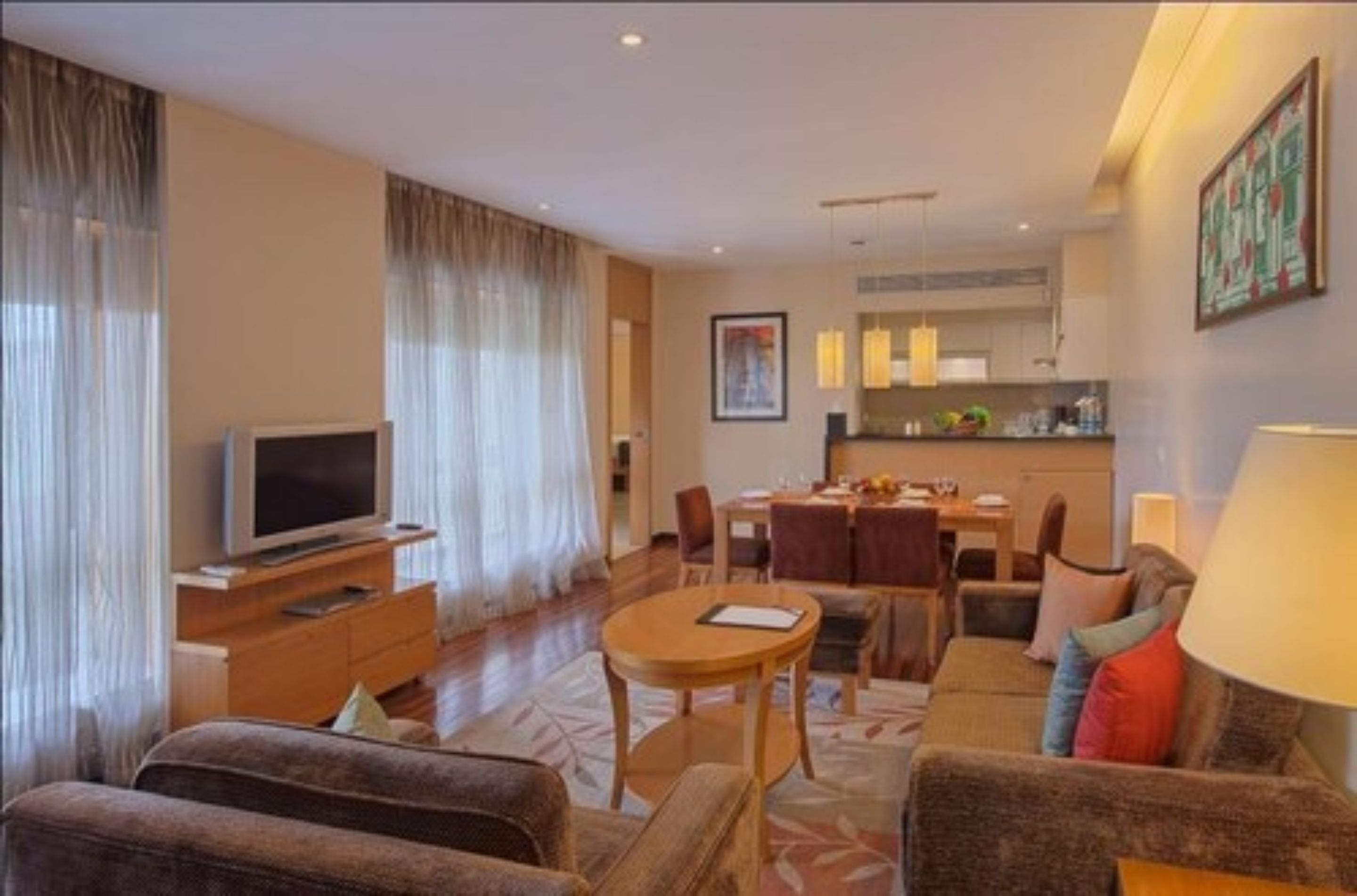A modern hotel room with a living area, dining space, and a kitchenette.