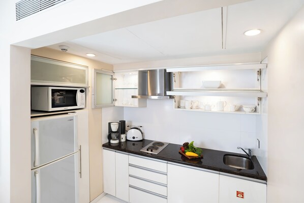 A modern kitchen with a microwave, toaster, sink, and cabinets. - Oakwood Residence Naylor Road Pune (Pune)