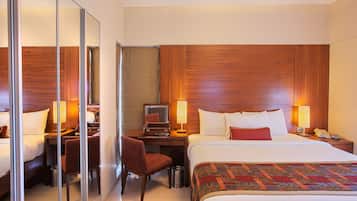 A hotel room with a bed, desk, chair, and a mirror.