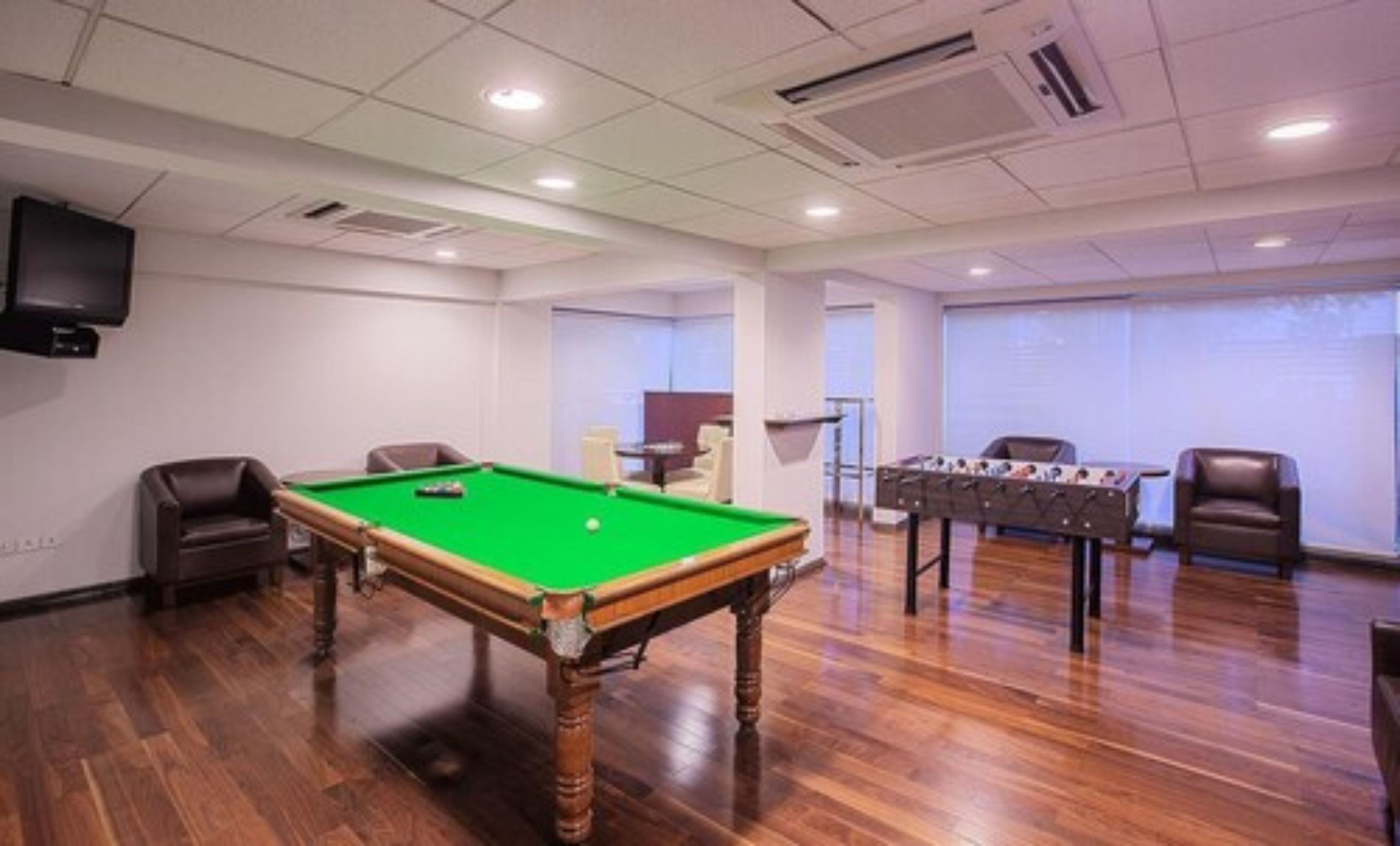 A room with a pool table, a foosball table, and a billiards table.