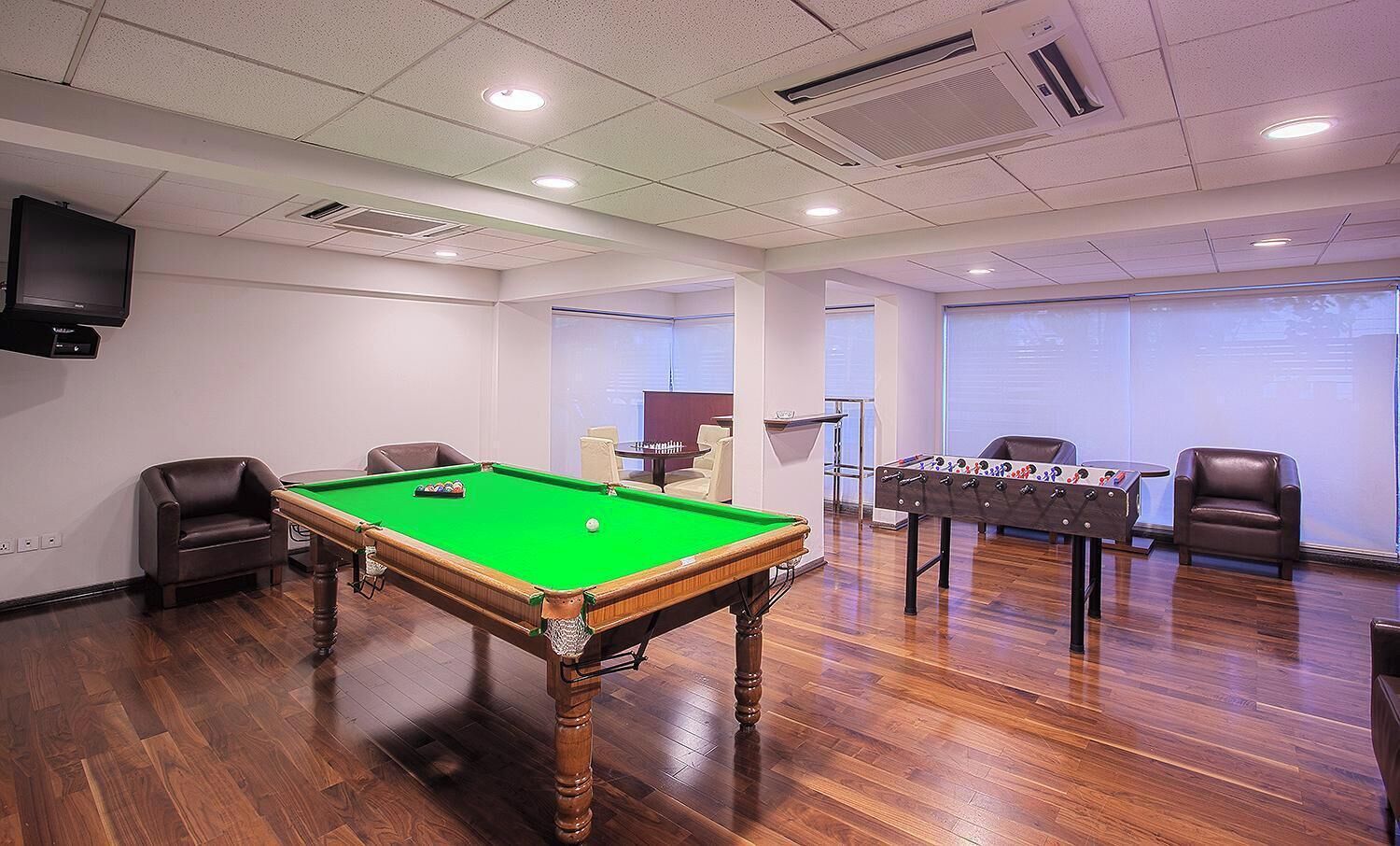 A room with a pool table, a foosball table, and a television.