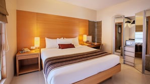 Una habitación de hotel con una cama grande, mesitas de noche, una lámpara, un teléfono y un espejo.